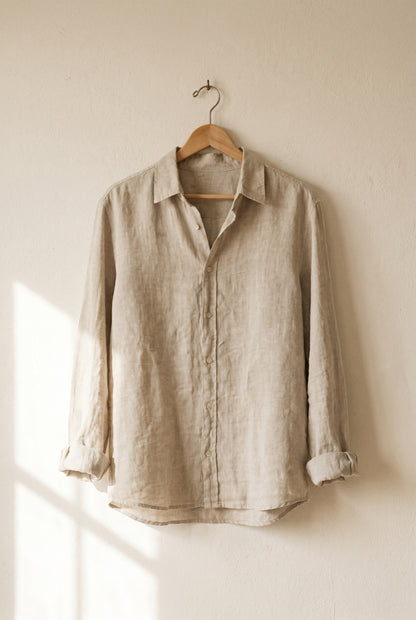 Natural stone linen shirt on a wooden hanger against a warm plaster wall