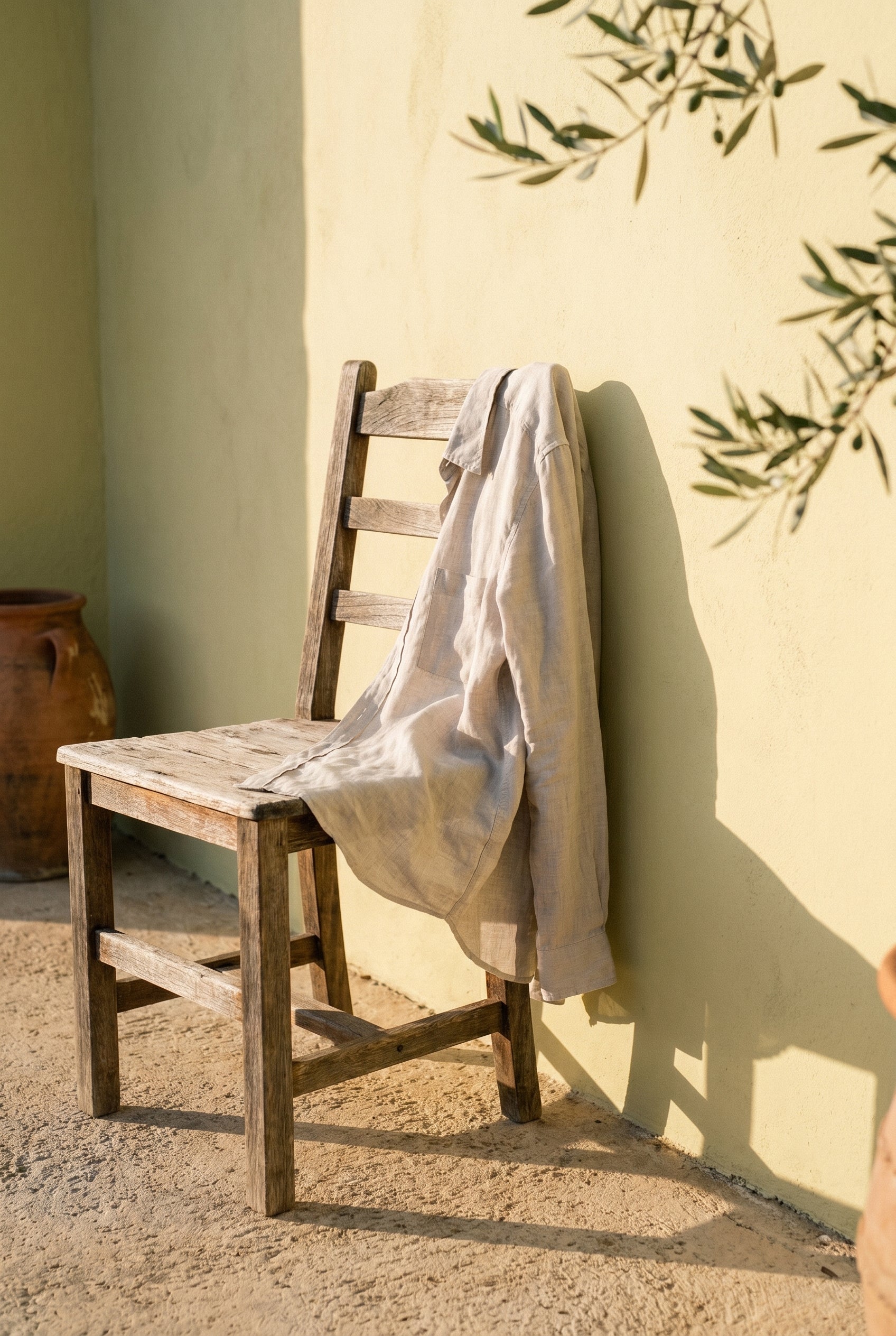 Natural stone linen shirt draped over a chair on a Mediterranean terrace